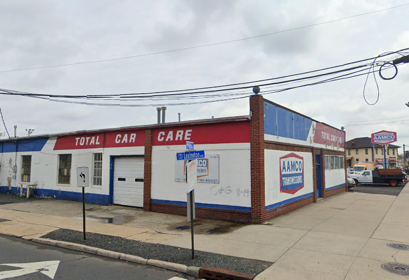 AAMCO auto repair shop with blue and gray exterior, large windows, and parking lot.