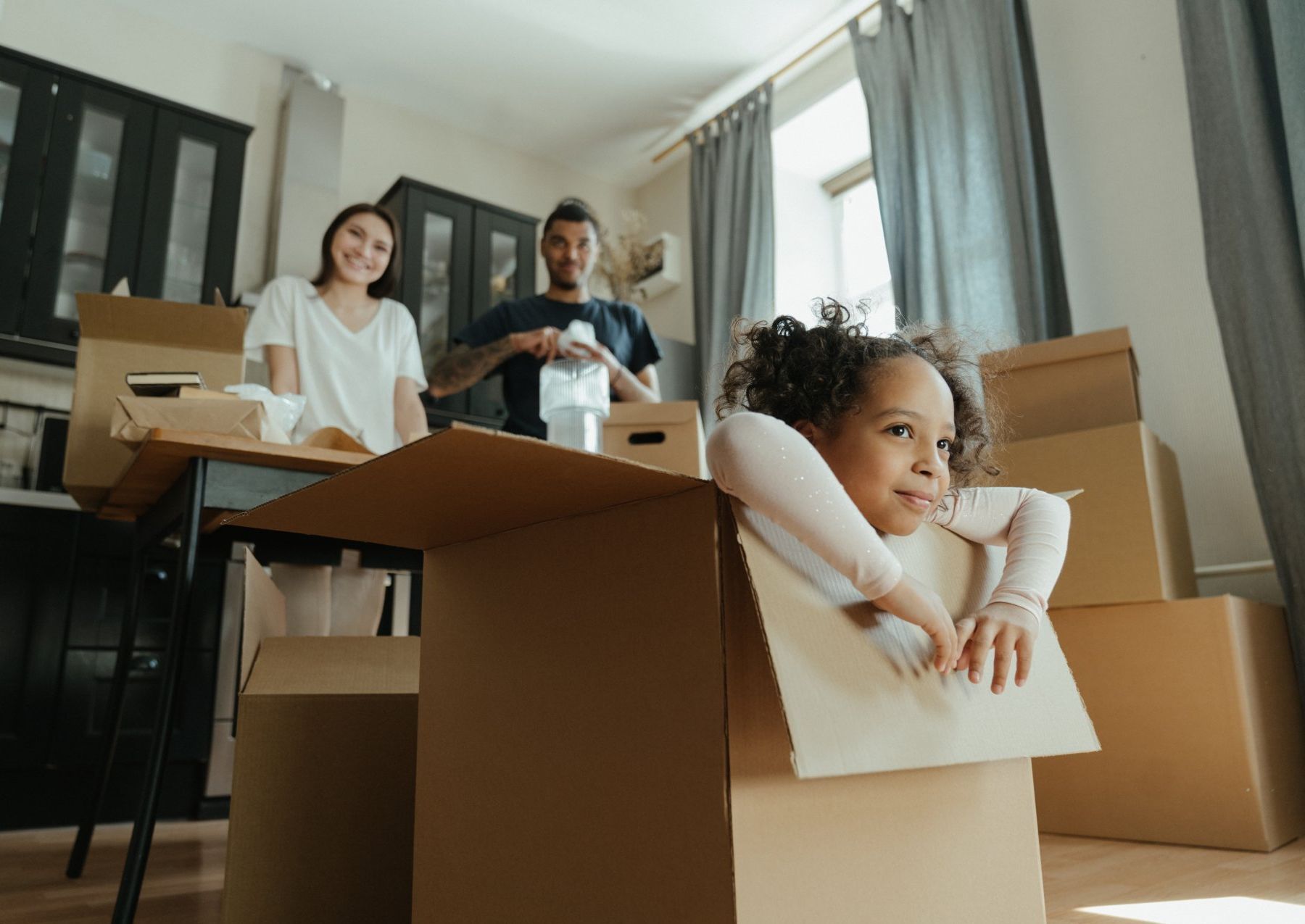A little girl is sitting in a cardboard box.