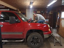 Person working under the hood of a red truck in a garage