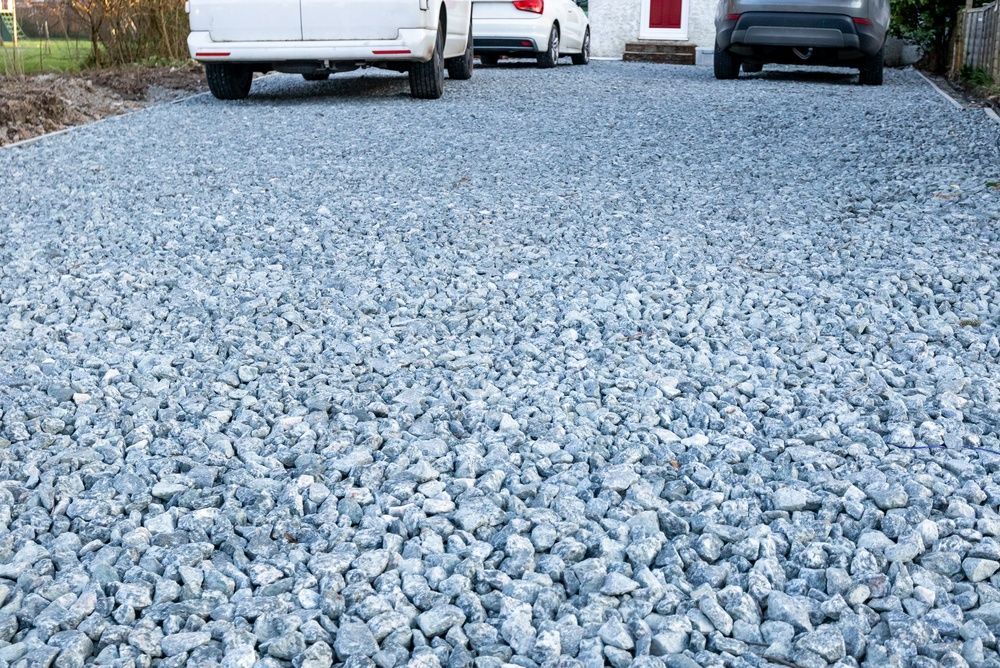 Gravel driveway with parked vehicles in the background
