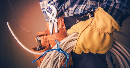 A man is holding a bunch of wires and a tool belt.