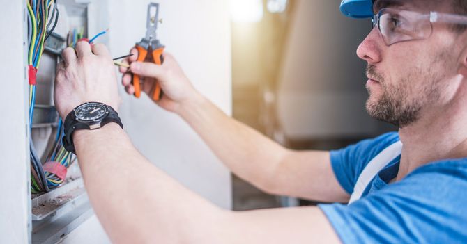 A man is working on a wall with a pair of pliers.