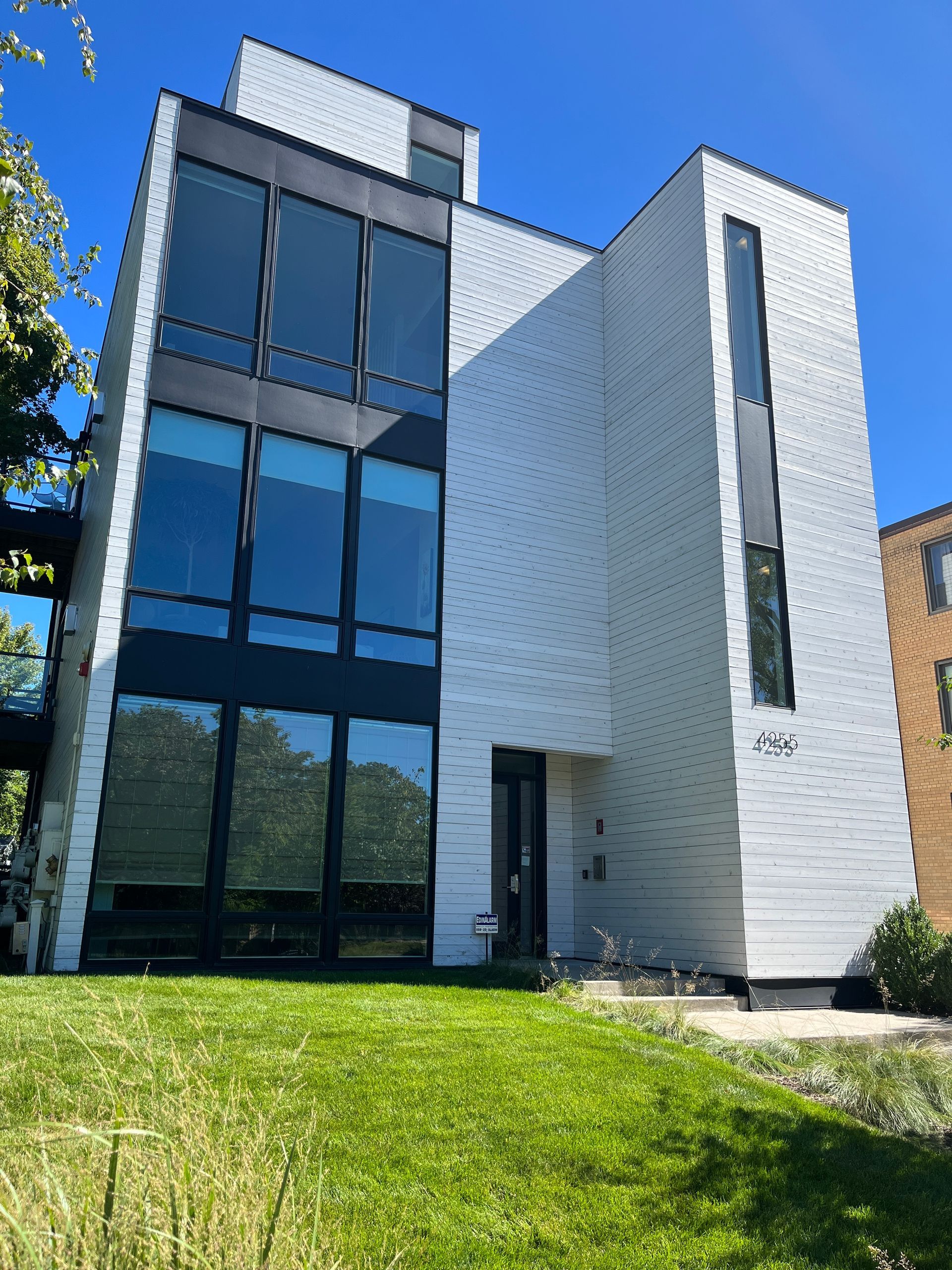 A large white building with a lot of windows is sitting on top of a lush green lawn.