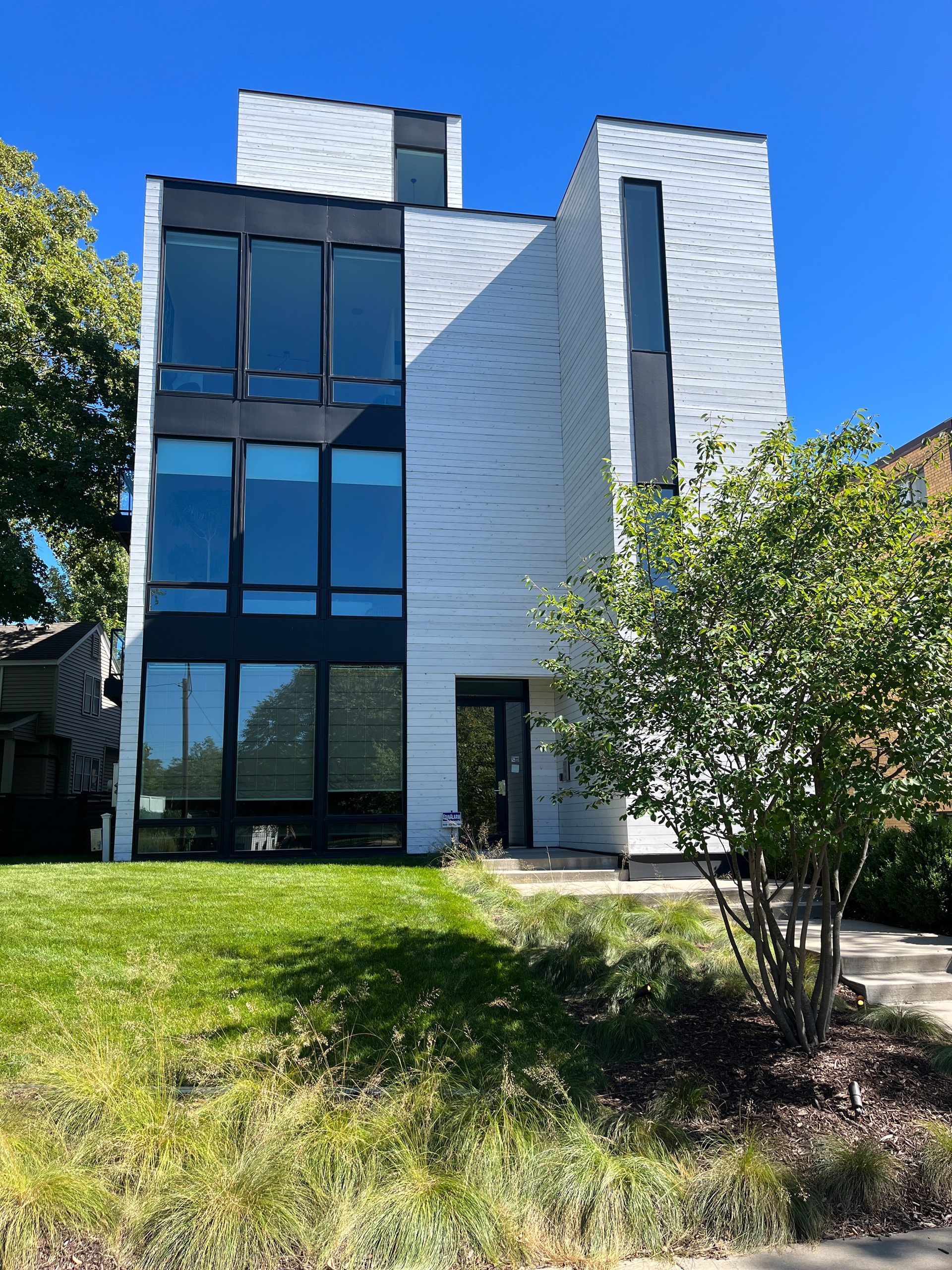 A large white building with a lot of windows is sitting on top of a grassy hill.