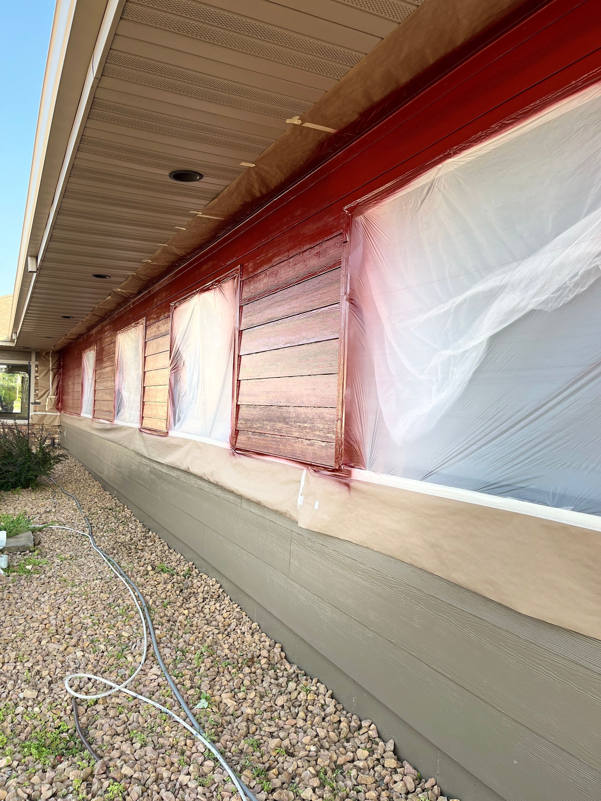 A house with a lot of windows is being painted red.