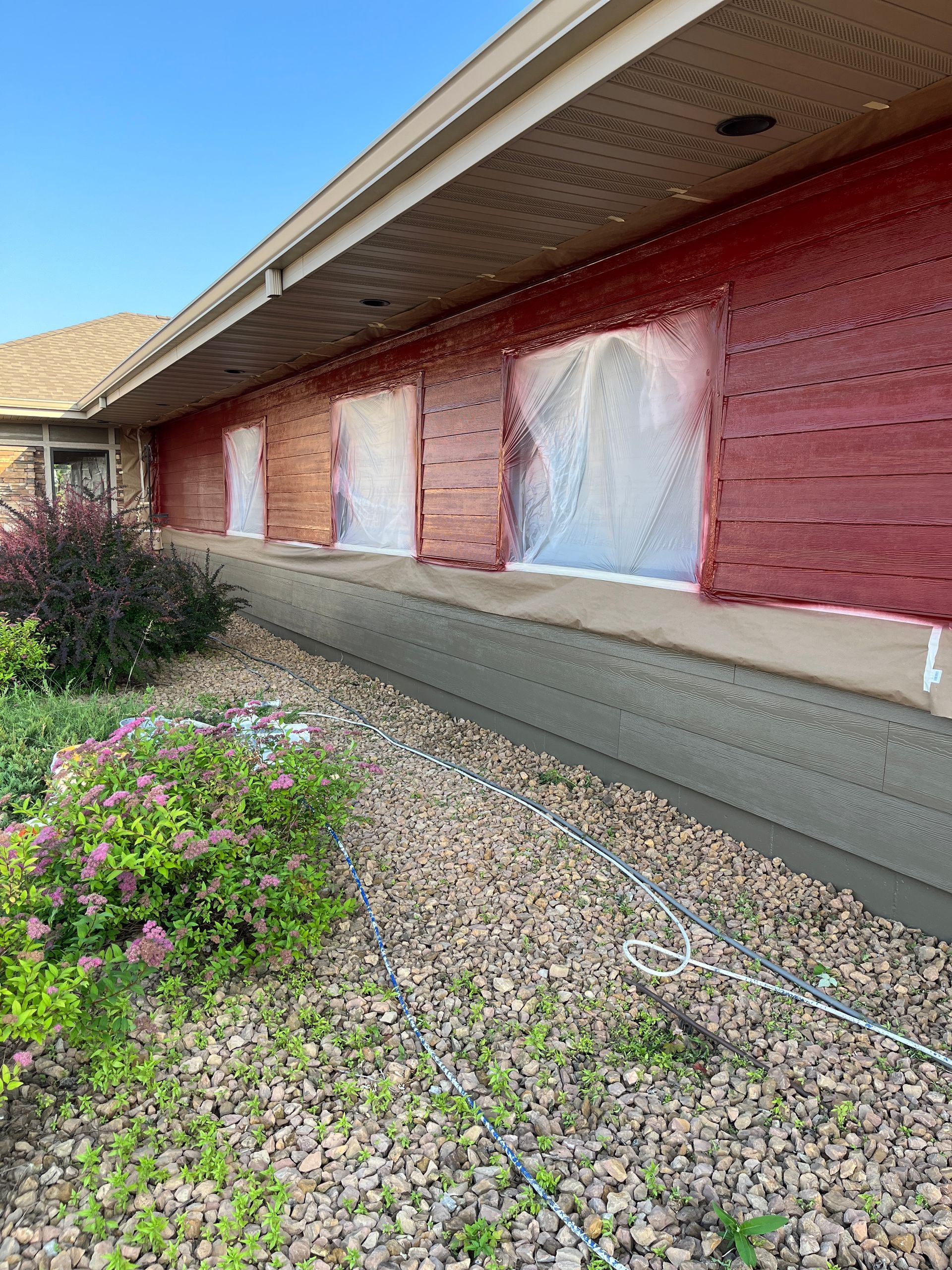 A house is being painted red and covered in plastic.