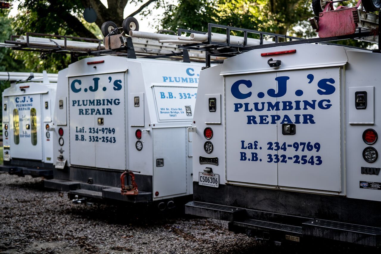 C.J.’s Plumbing Repair trailers parked outdoors, with blue lettering on white equipment