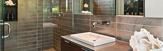 Modern bathroom with tiled walls, glass shower, vessel sink, and white towels on a countertop
