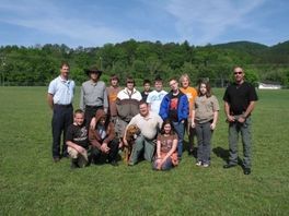 A group of people are posing for a picture in a grassy field.