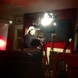 A man in a cowboy hat is standing in a dark room.