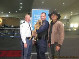 Three men are standing next to each other holding a dog.