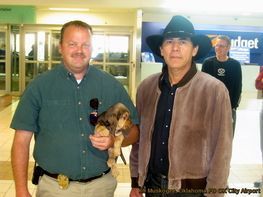 A man in a cowboy hat is holding a small dog