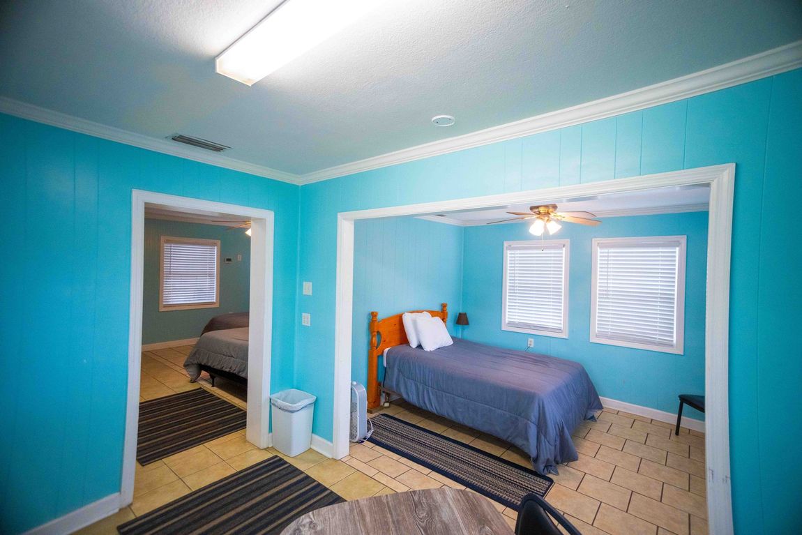 Turquoise bedroom with blue bedspread, two doorways, and tiled floor in a bright home interior
