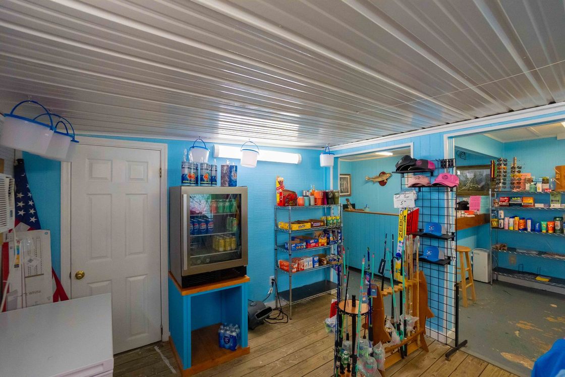 Small blue-and-white shop interior with snack racks, cooler, and a white door