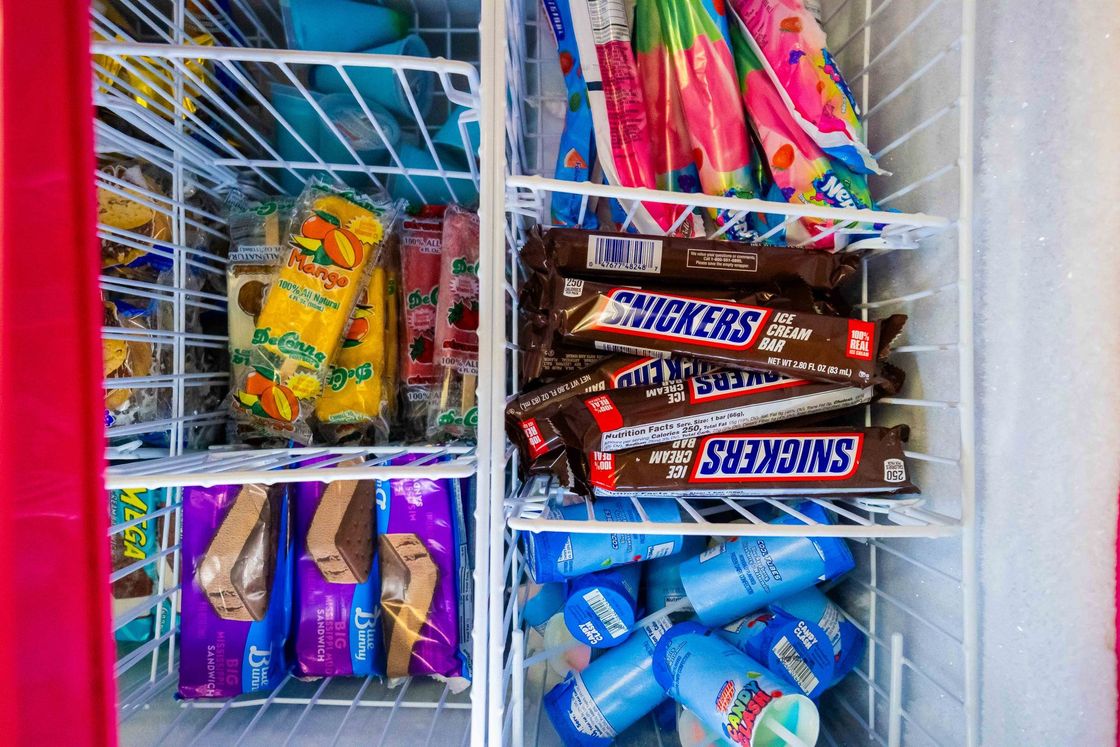 Assorted candy bars and snacks in a colorful display rack inside a store.