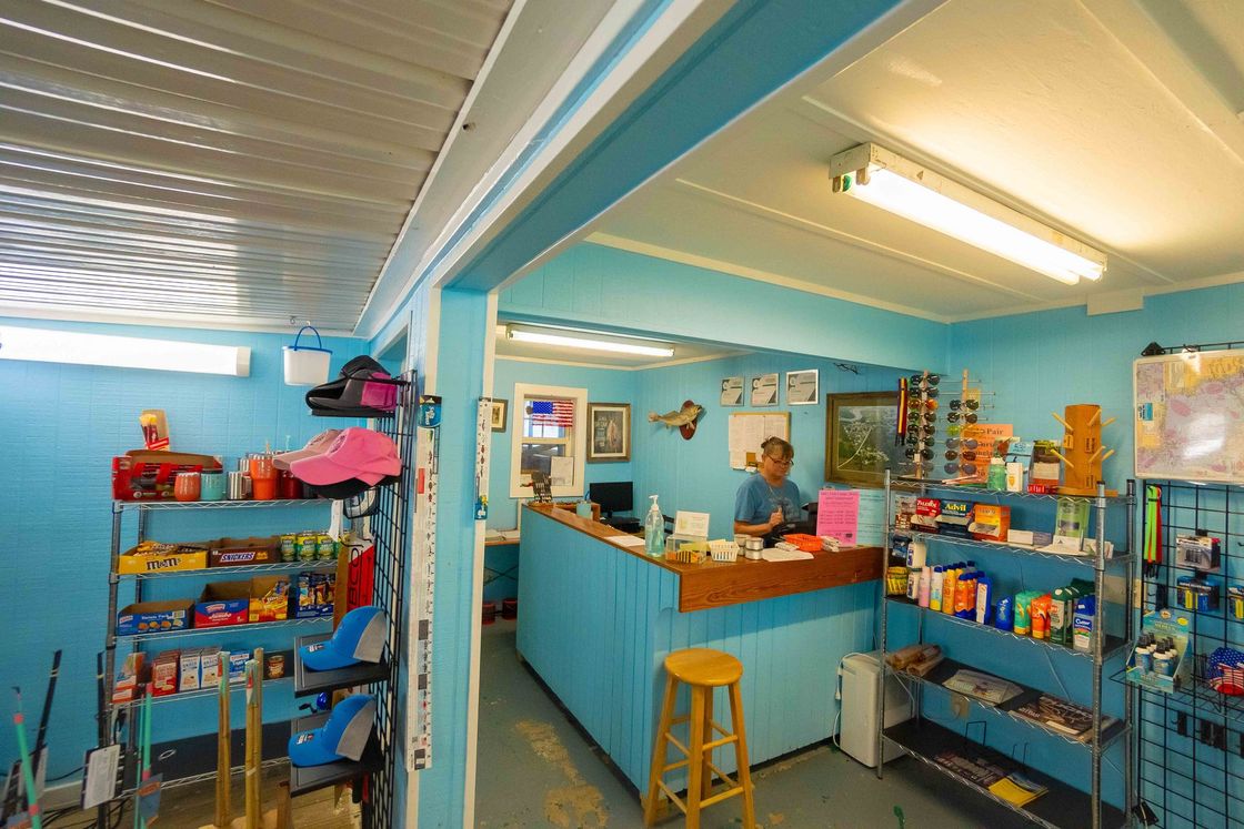 Bright turquoise shop interior with shelves of colorful products and a wooden counter under fluorescent lights