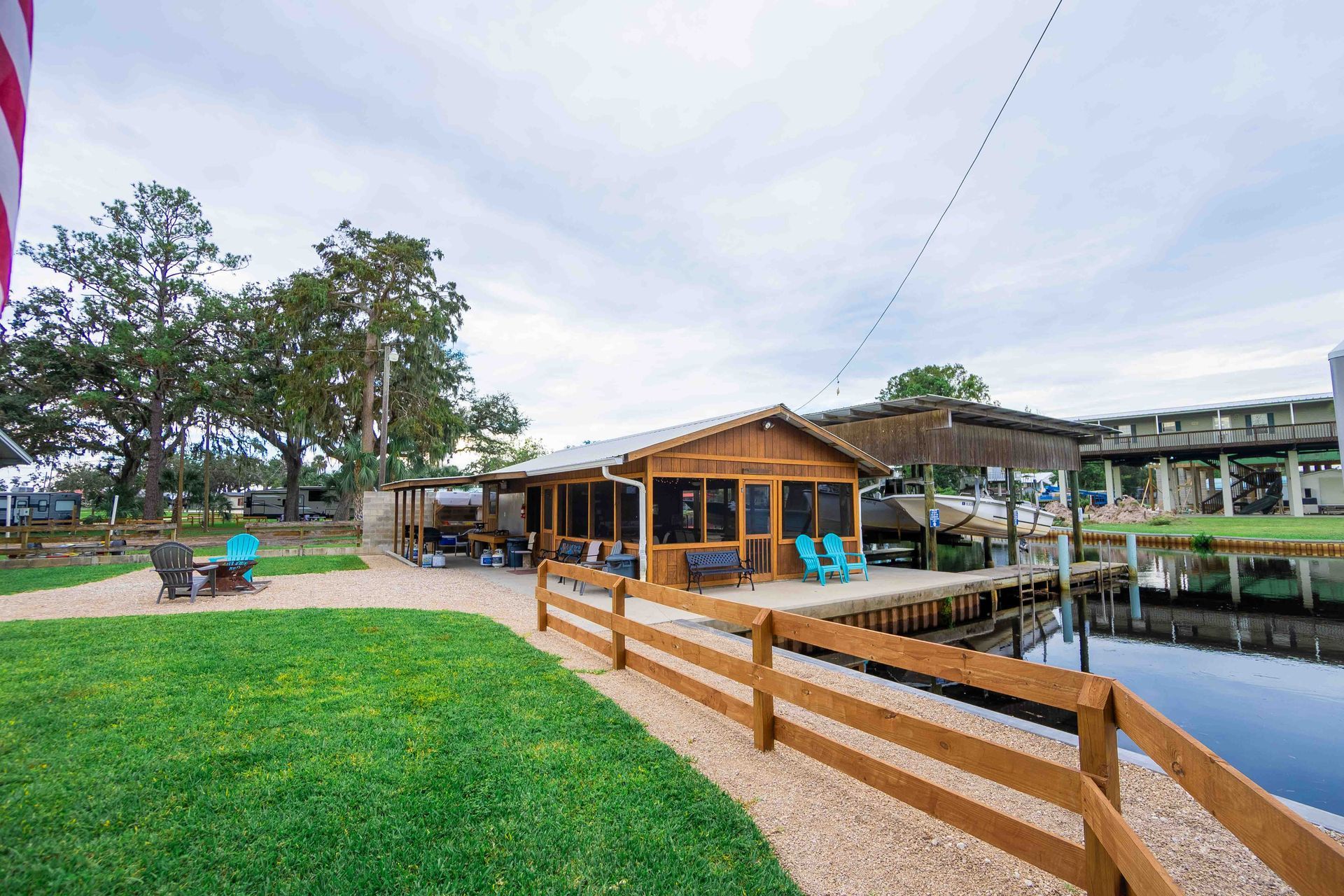 Wooden lakeside pavilion with a deck, grassy lawn, and people seated near the water