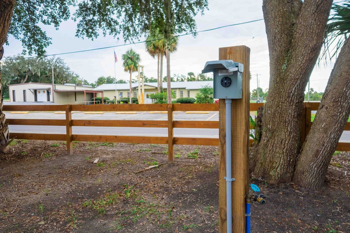 Mailbox on a wooden post by a fence and large tree in a backyard.