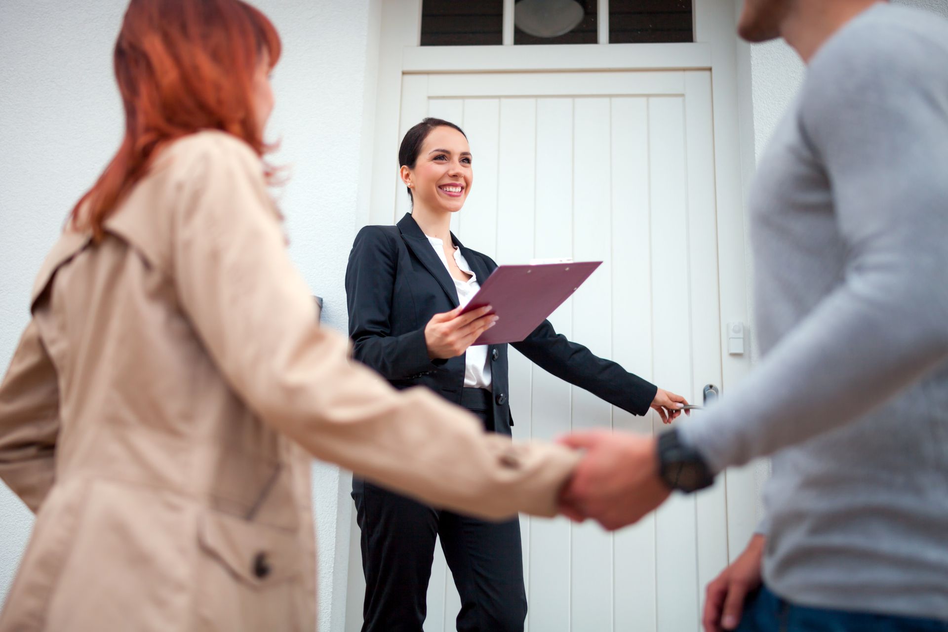 Real estate agent near door inviting young couple to enter house for visit. Real estate agent near door inviting young couple to enter house for visit.