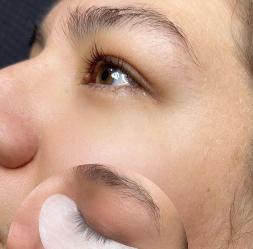 A close up of a woman 's eye with lashes being applied