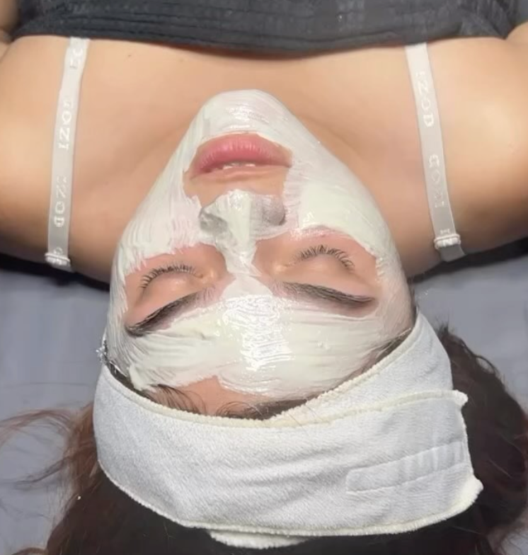 A woman is laying down with a white mask on her face