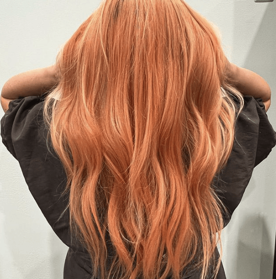 A woman with long peach hair is wearing a black shirt.