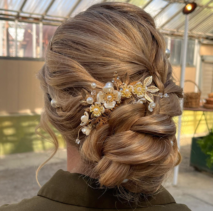 A woman is wearing a bun with a comb in her hair.