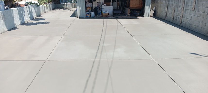 Wide concrete driveway leading to a garage or loading area beside a brick wall