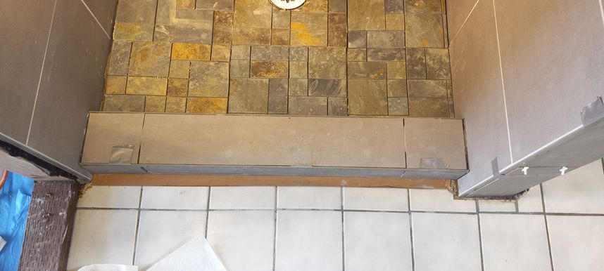 Bathroom threshold with tiled floor and a raised step into a shower area