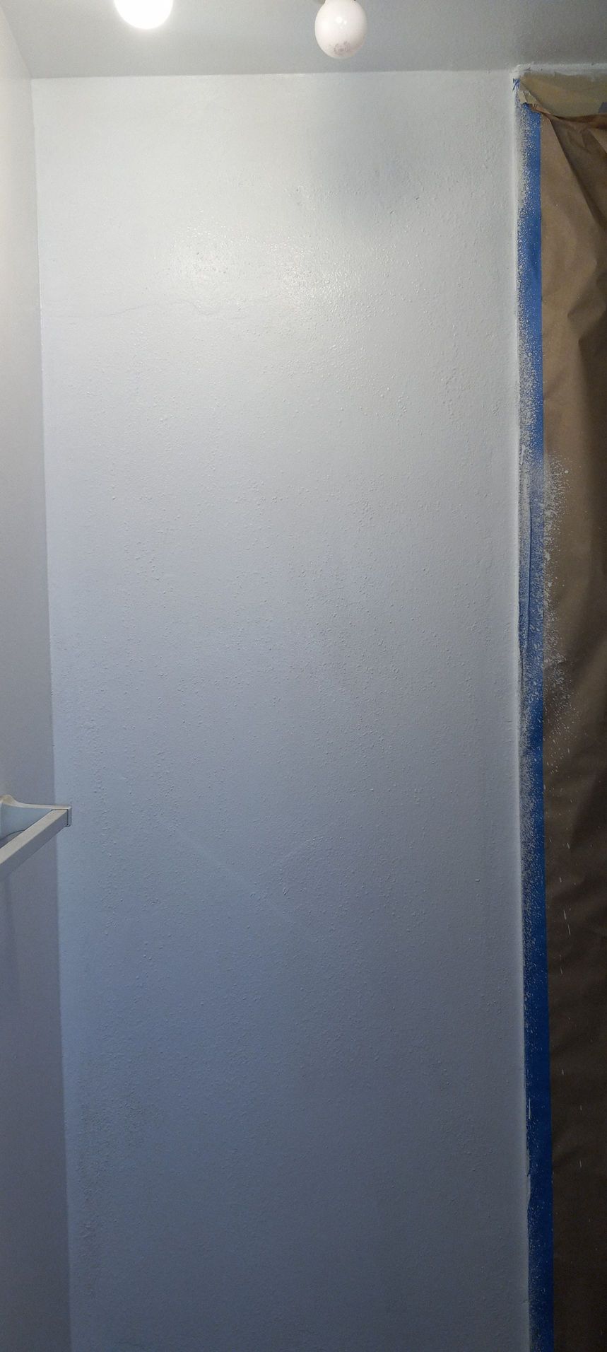 Narrow white hallway with a ceiling light and a partially visible doorway on the right