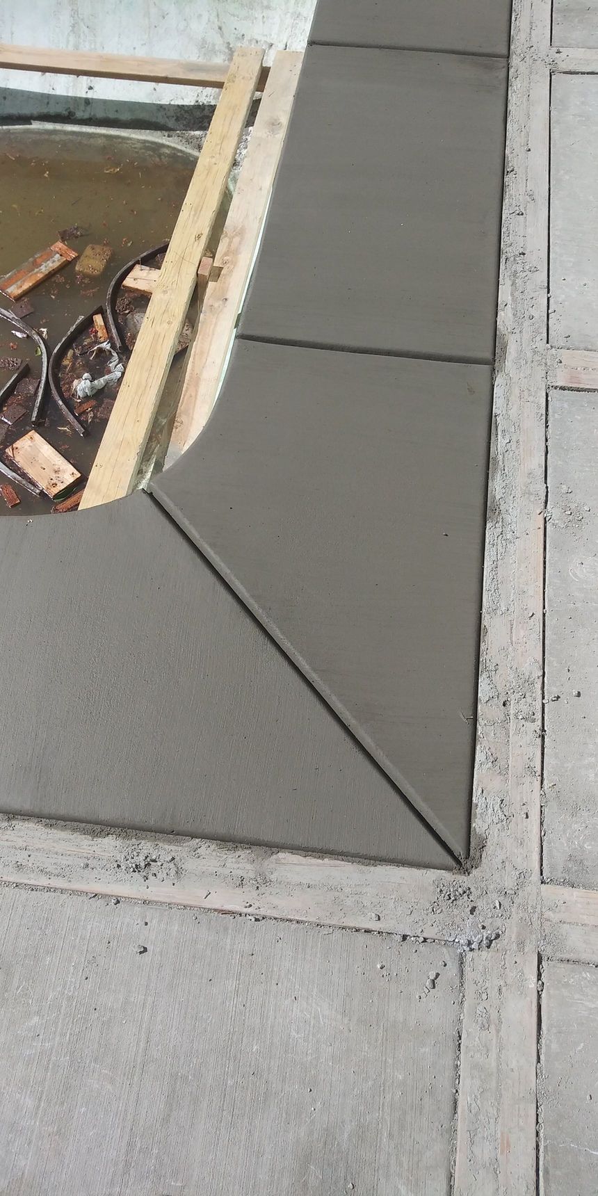 Fresh gray concrete patch beside an exposed opening on a construction site