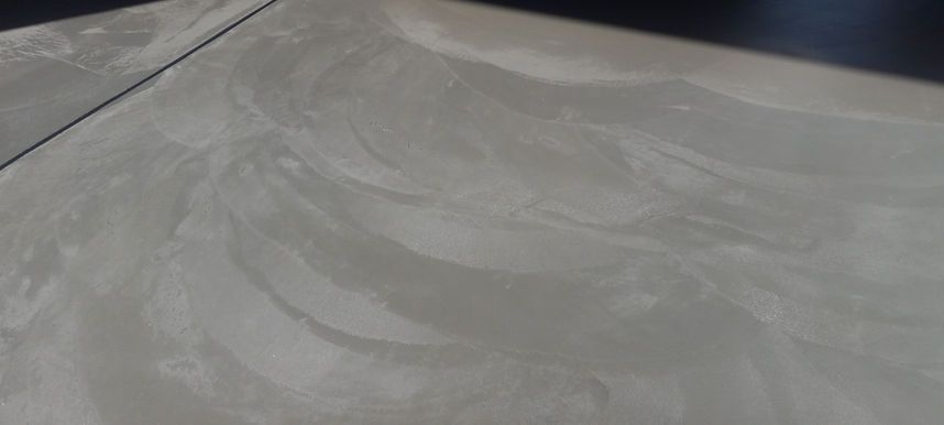 Empty gray concrete surface with subtle swirl patterns and a dark edge in the background