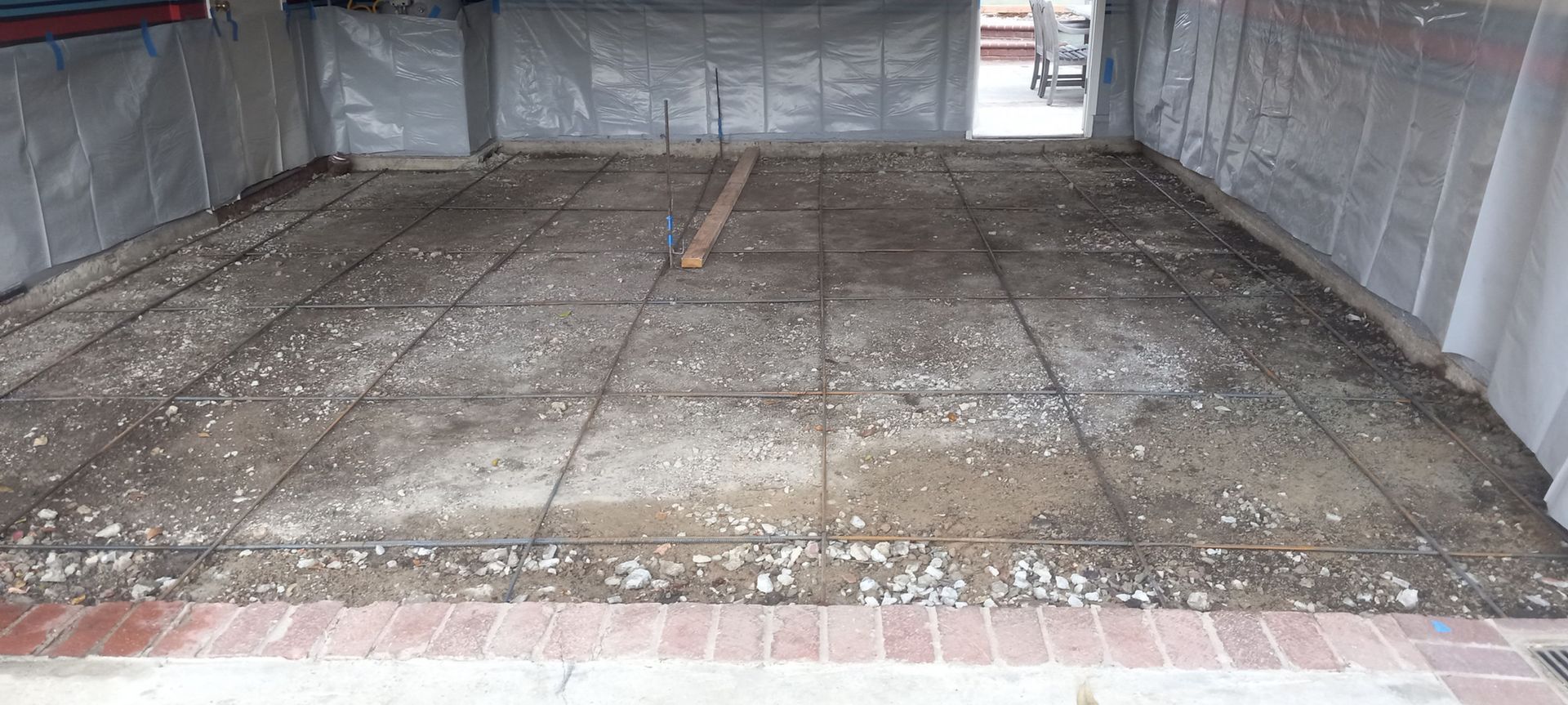 Empty covered garage floor with concrete panels and brick edge, viewed from inside a tented structure