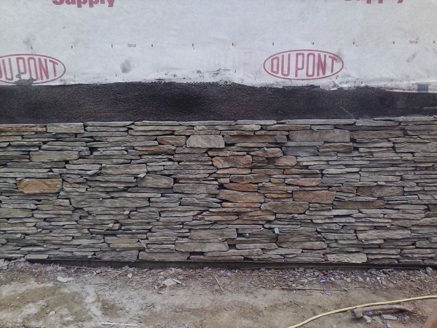 Stone veneer wall beneath a white wall with red DuPont logos, viewed close up.