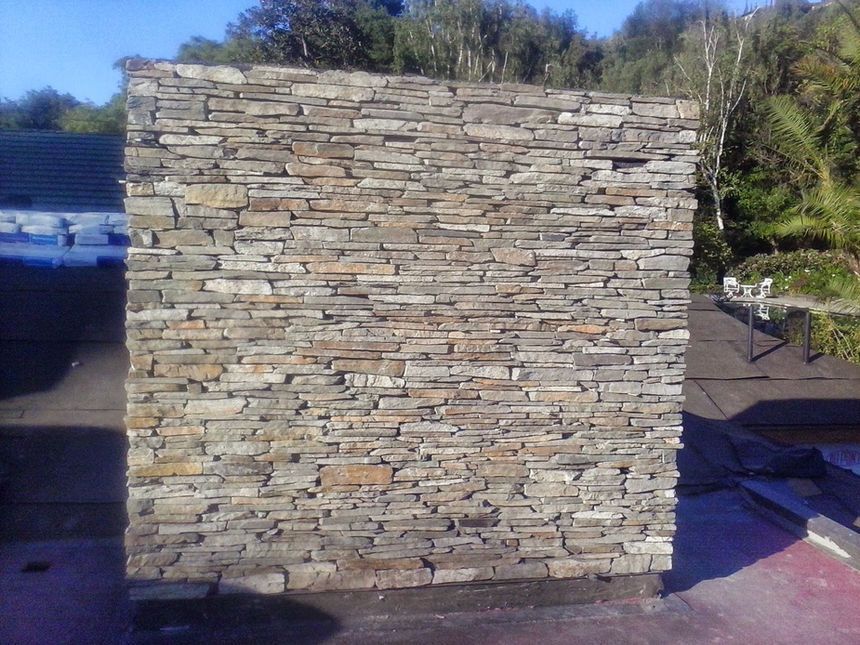Stone wall built from stacked flat stones outdoors in sunlight