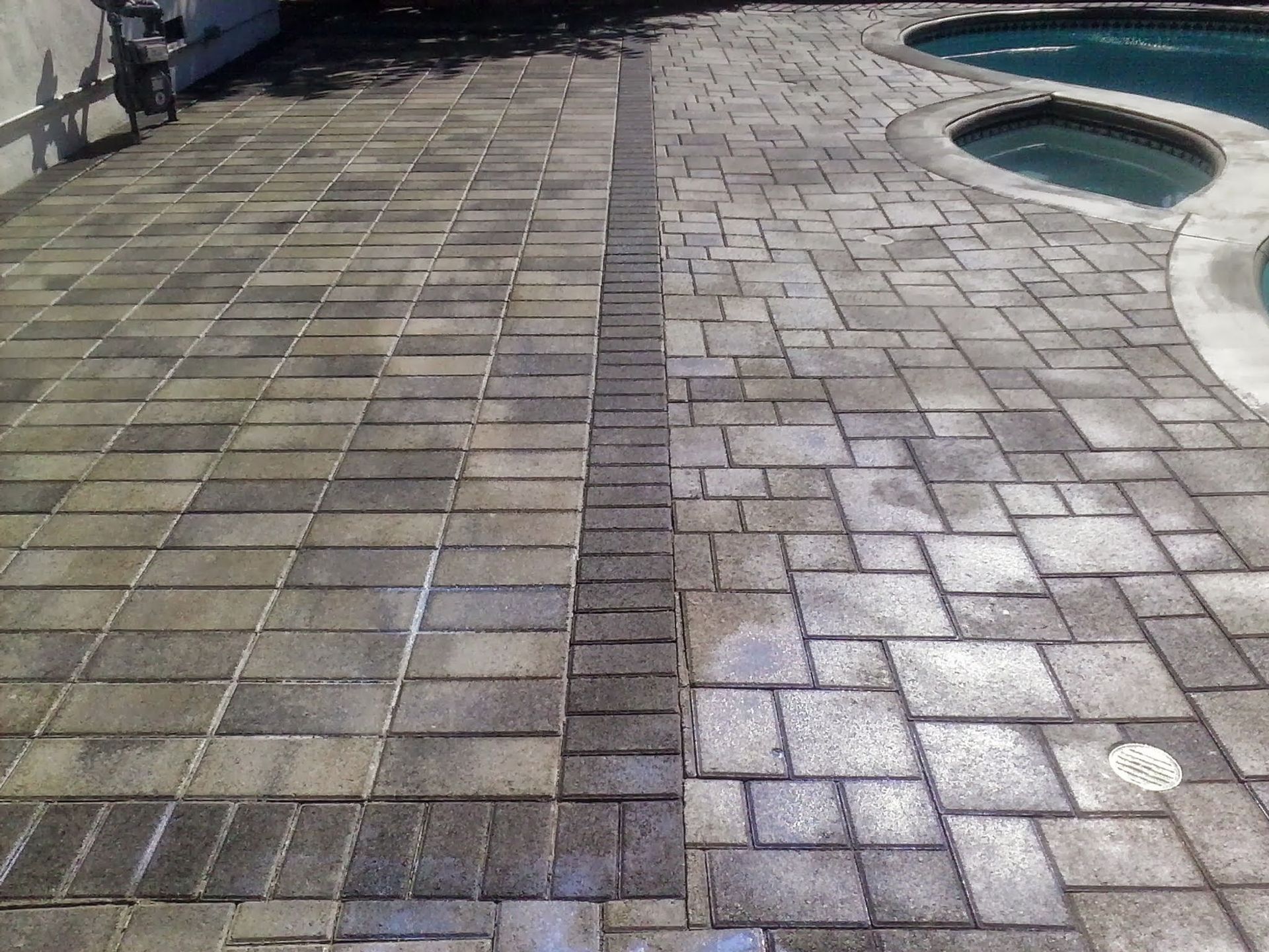 Paved courtyard with a curved pool edge and a central strip of darker bricks.