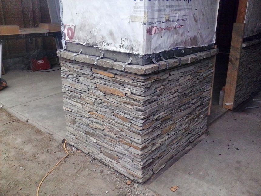 Stone veneer wrapping the base of a building column under construction