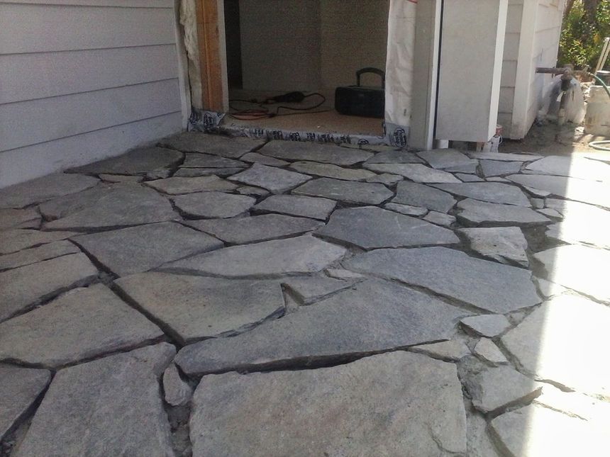 Stone-paved front porch with large irregular flagstones beside a house entrance