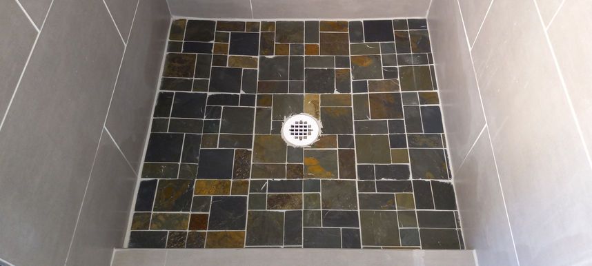 Tiled shower floor with a central drain and light gray walls