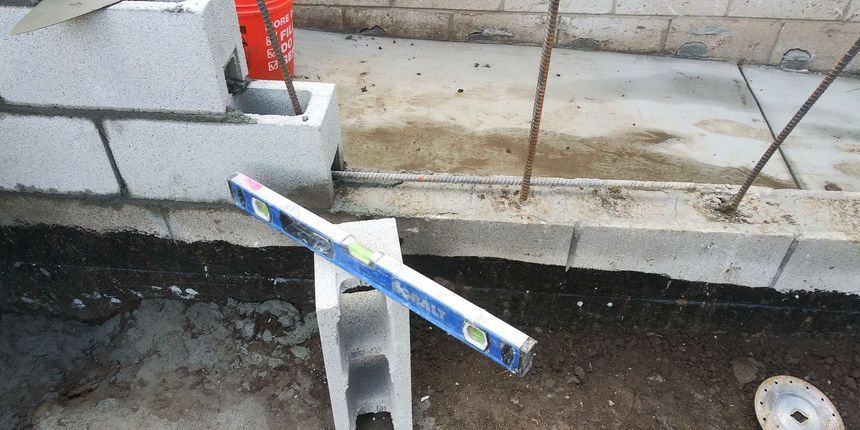 Metal support post with a blue-and-white measuring level on a curbside construction area