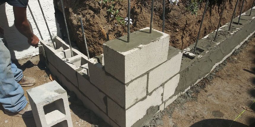 Masonry wall under construction with stacked concrete blocks and rebar at a building site