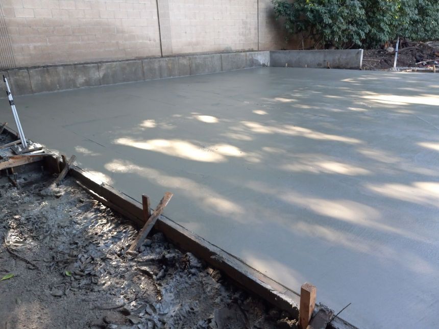 Freshly poured concrete slab bordered by wooden forms in an outdoor construction area