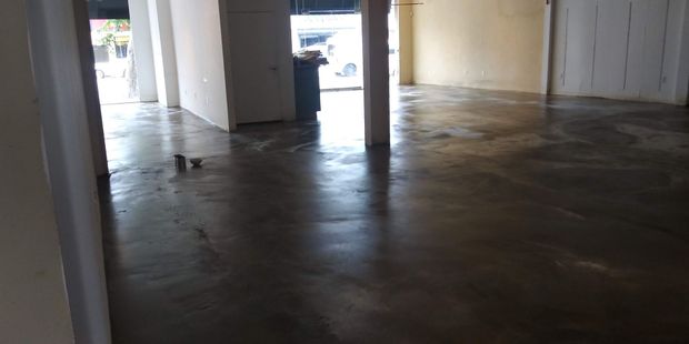 Empty industrial room with concrete floor, white walls, and daylight through an open doorway