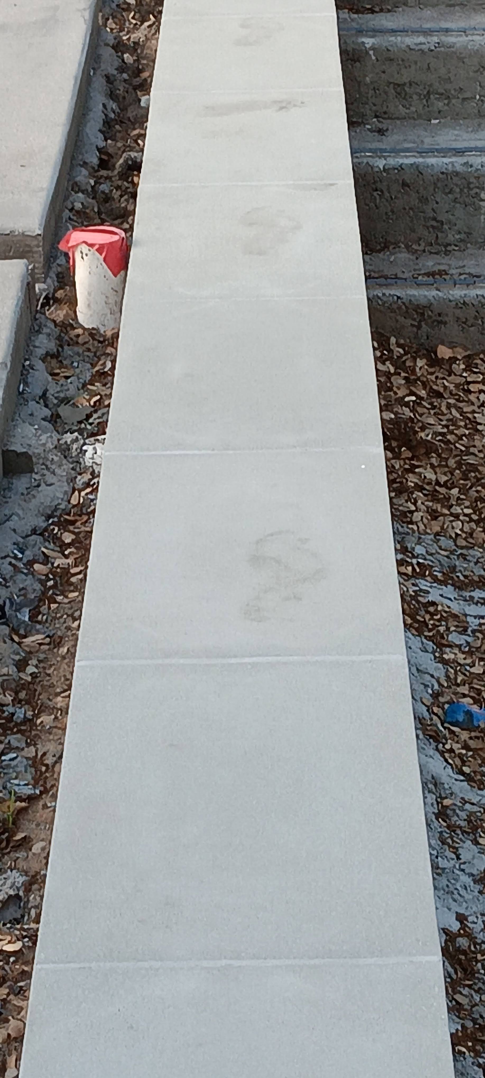 Long white board laid across railroad tracks beside gravel and a red can.