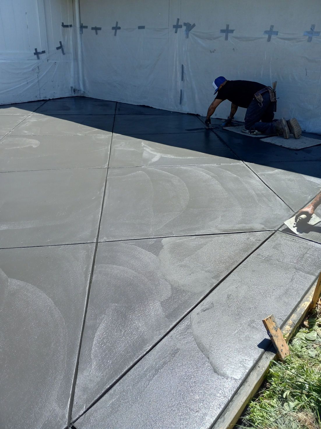 Worker applying waterproof coating on a rooftop deck under bright sunlight
