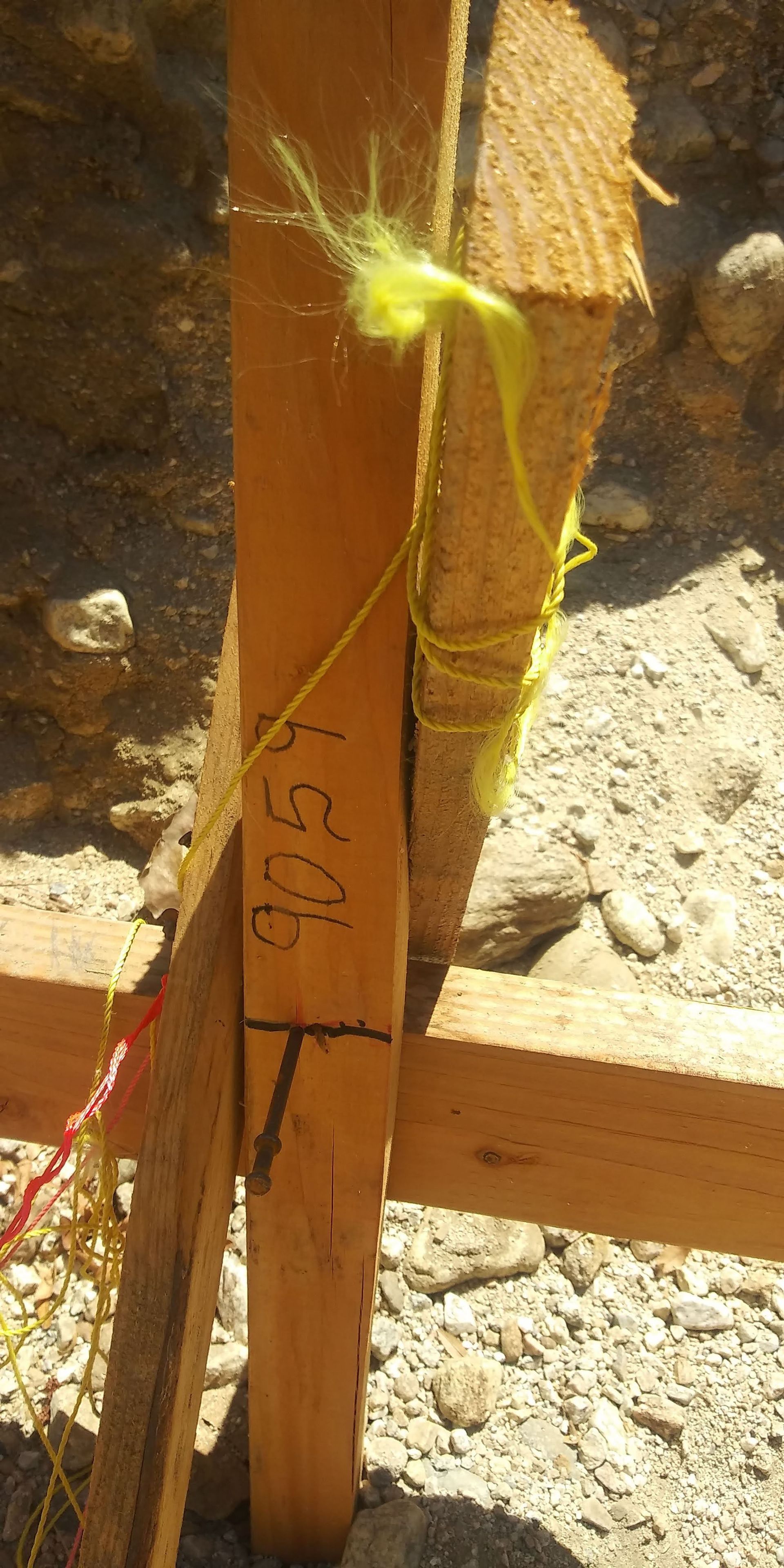 Close-up of a yellow string tied to a wooden post in a dusty outdoor construction area