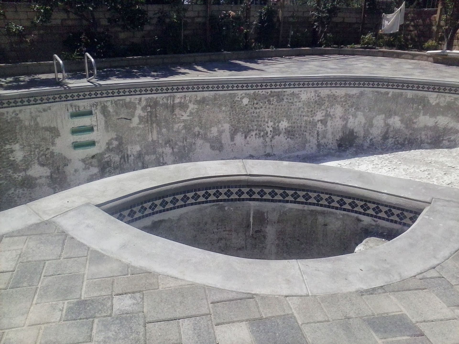 Empty outdoor swimming pool with a small oval spa inset in the concrete deck