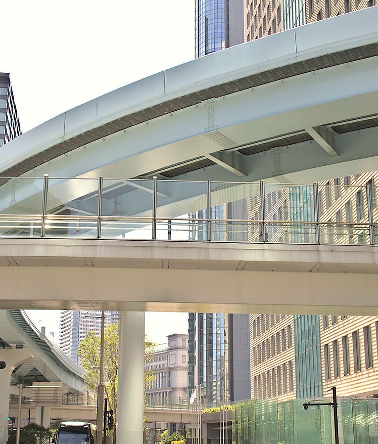 Curved pedestrian skybridge between tall glass buildings in a modern cityscape