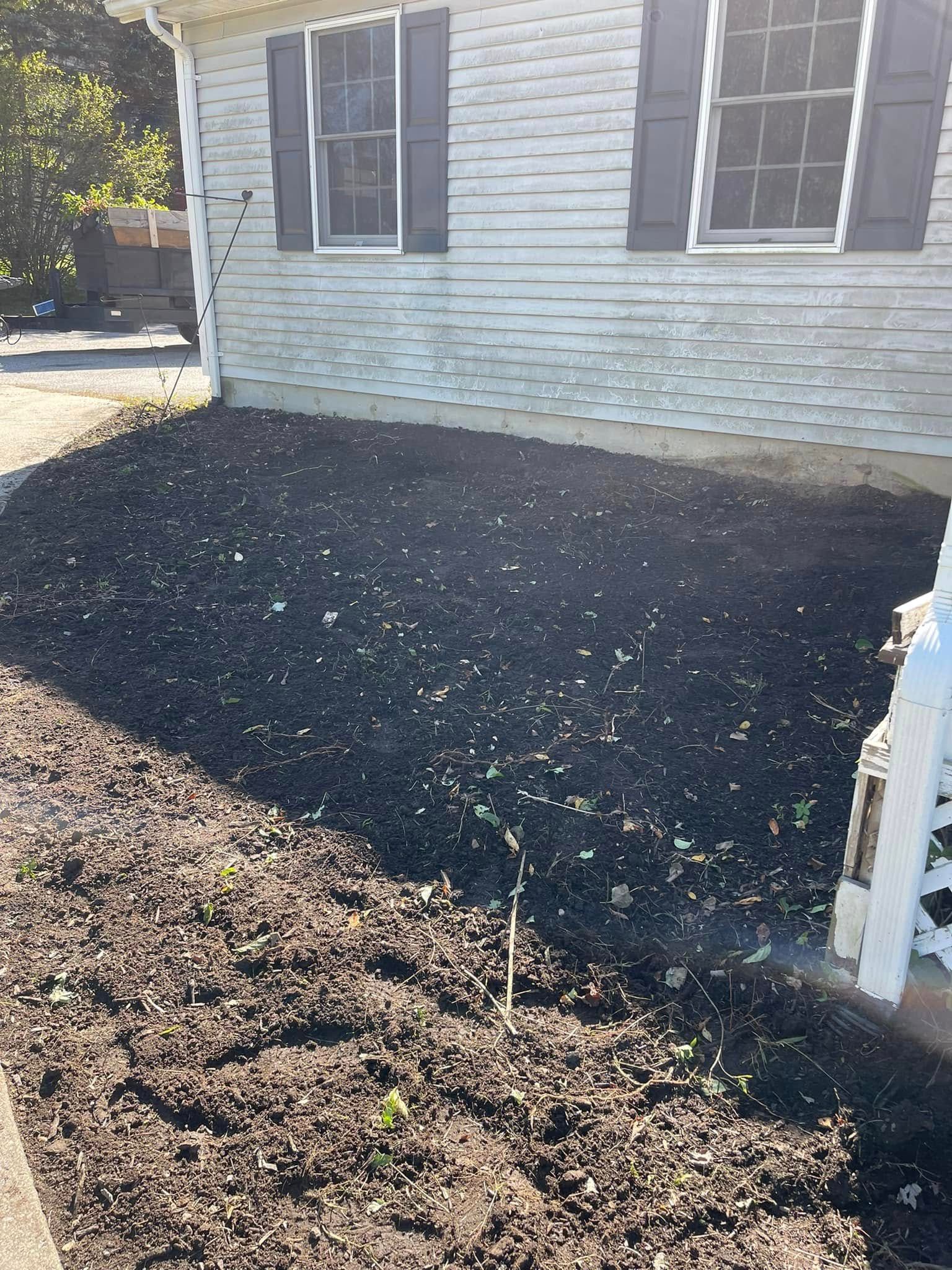 House exterior with fresh black mulch bed along the foundation and white siding.