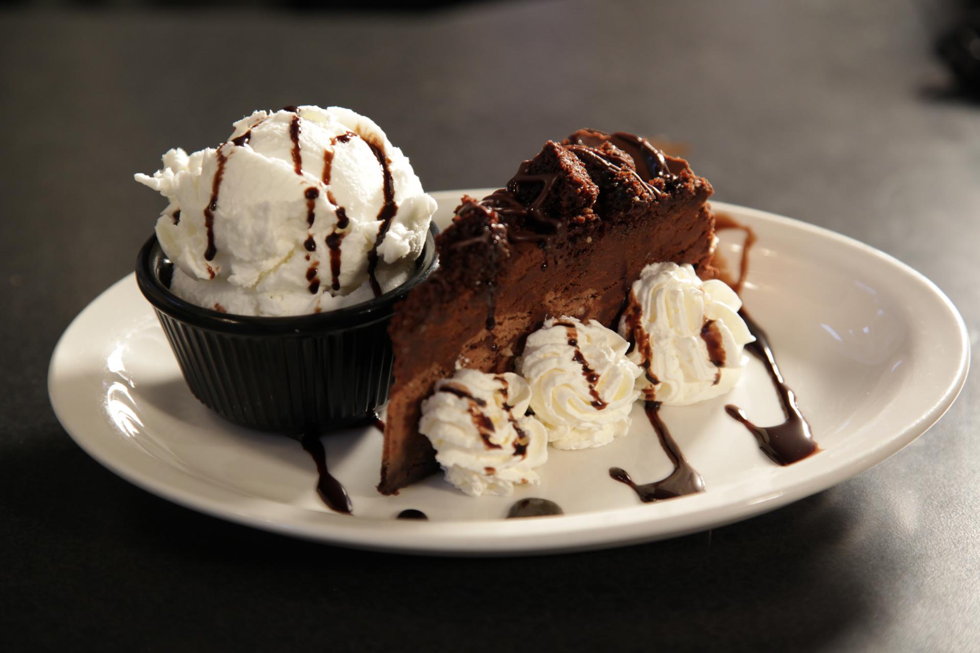 A chocolate pie with whipped cream and chocolate sauce on a white plate.